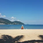Pessoa desfrutando de exposição solar controlada em praia brasileira, otimizando vitamina D.