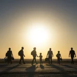 Direitos de Refugiados e Migrantes no Brasil: Guia 2025 Grupo diverso de refugiados e migrantes caminhando em direção ao pôr do sol, simbolizando esperança no Brasil.