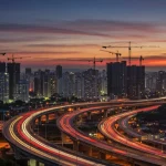 Infraestrutura no Brasil em 2025: R$ 150 Bilhões e Projetos Prioritários Skyline de uma cidade brasileira moderna ao anoitecer, com guindastes de construção, simbolizando o desenvolvimento de infraestrutura no Brasil em 2025.